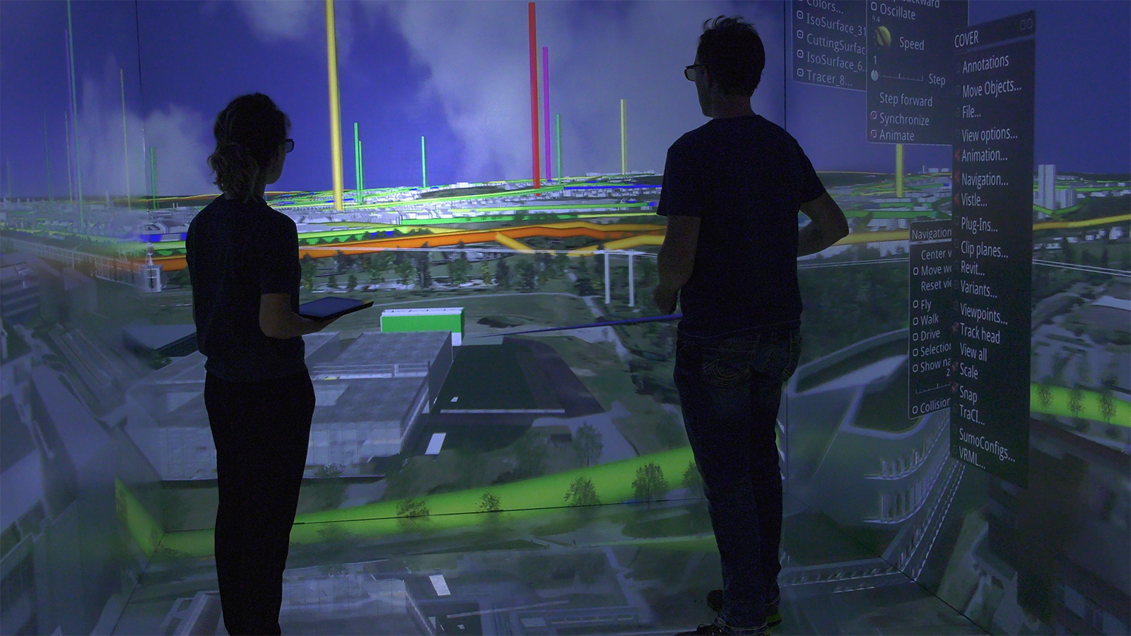 Two scientists observe a room-sized, projected visualization of the University of Stuttgart campus.